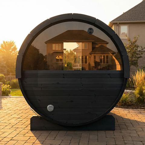 SaunaLife E7WB black barrel with half-moon window on stone patio at sunset